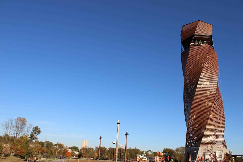 A tall, twisted metal tower with a flat top, surrounded by trees and street lamps. 4