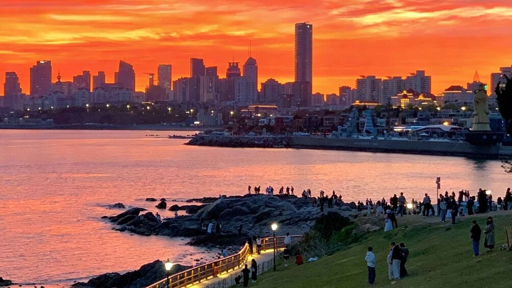 A sunset over a city skyline with a waterfront promenade. 1