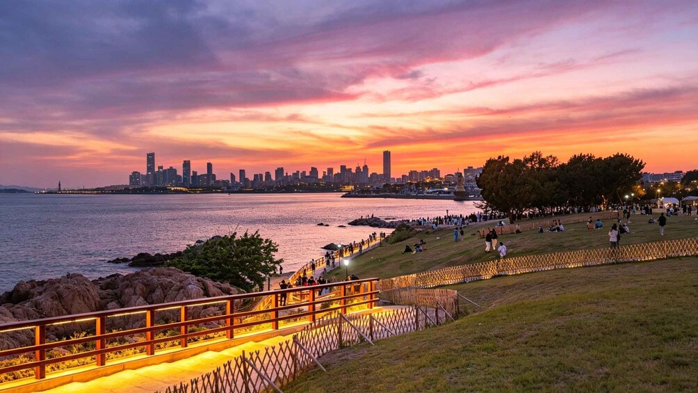A sunset over a city skyline with a park and a waterfront promenade. 5