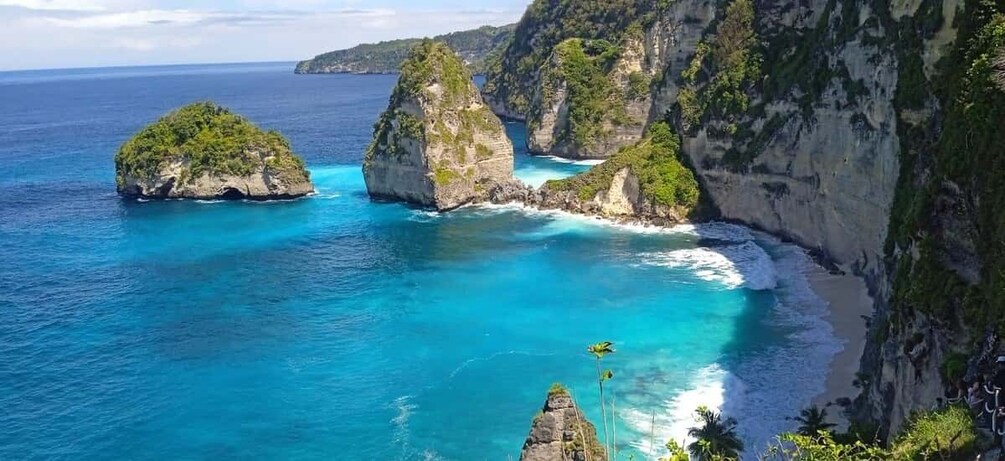 A coastal landscape with clear turquoise waters, rocky cliffs, and lush greenery. 3