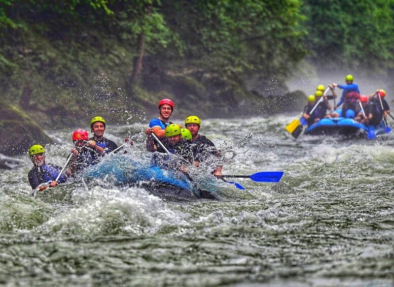 A group of people in a blue raft navigating through a river surrounded by trees. 5