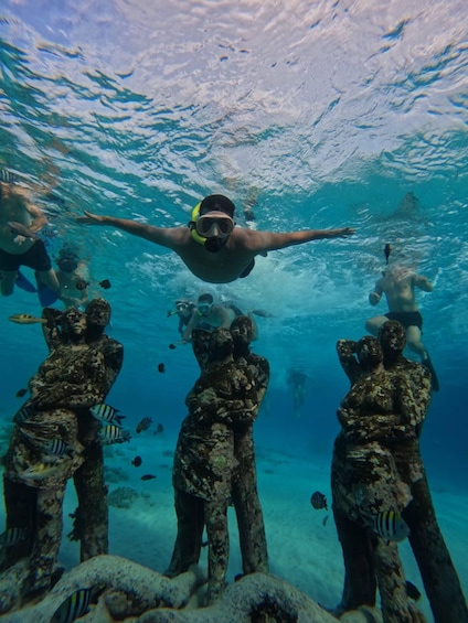 A diver swimming underwater with a group of divers and fish. 2