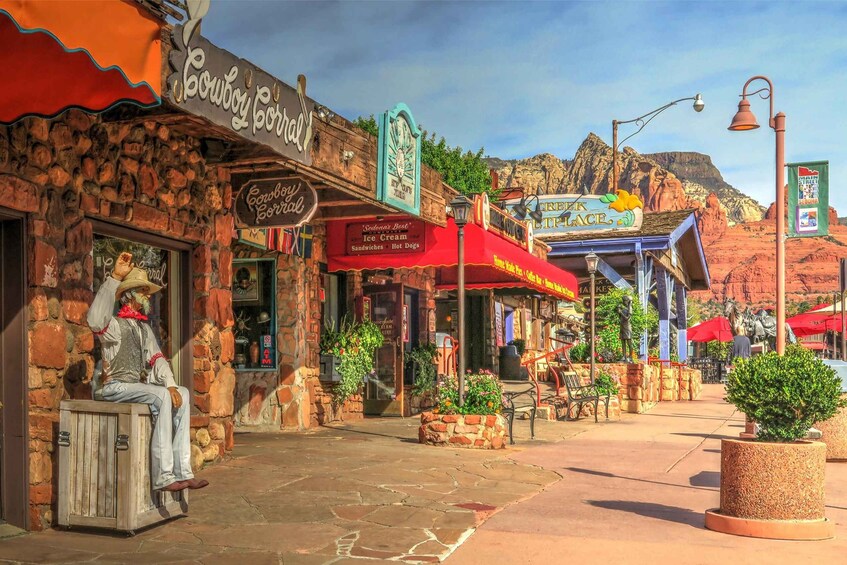 A Western-themed storefront with a cowboy statue, a clock, and signs for 'Cowboy Corral' and 'Creek Cafe.' 1