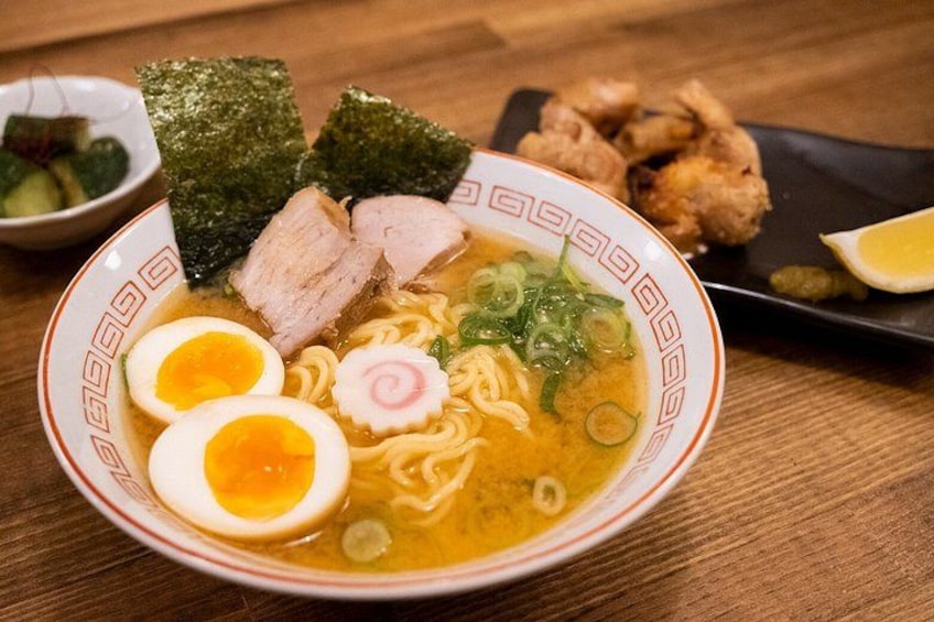 A bowl of ramen with sliced pork, boiled egg, and seaweed garnish. 1
