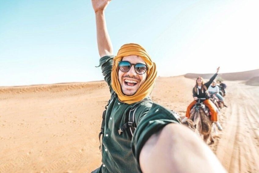 Una persona si fa un selfie con un gruppo di cammelli nel deserto. 2