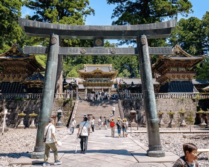A traditional Japanese torii gate with visitors walking through it. 5