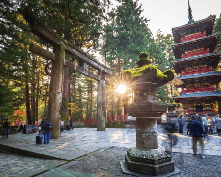 A stone statue in a forested area with a traditional building in the background. 2