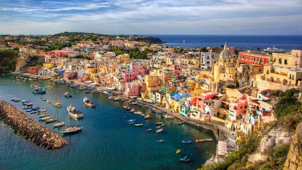 A coastal town with colorful buildings, a harbor with boats, and a clear view of the sea. 1