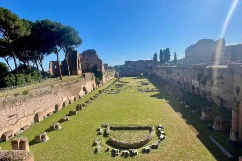 Ancient ruins with a circular stone structure in the center, surrounded by a grassy area and stone walls. 3