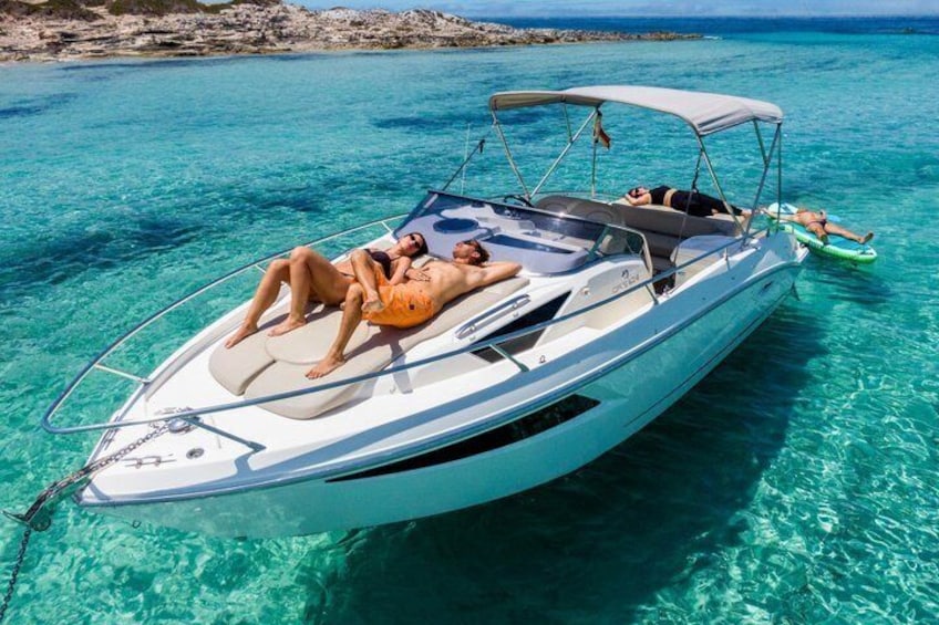 Un bateau à moteur blanc, doté d’un auvent, avec deux personnes allongées sur le pont, et une eau turquoise cristalline. 3