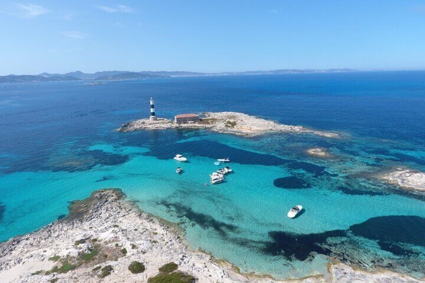 Un paysage côtier avec un phare, des bateaux et une eau d’un bleu limpide. 1