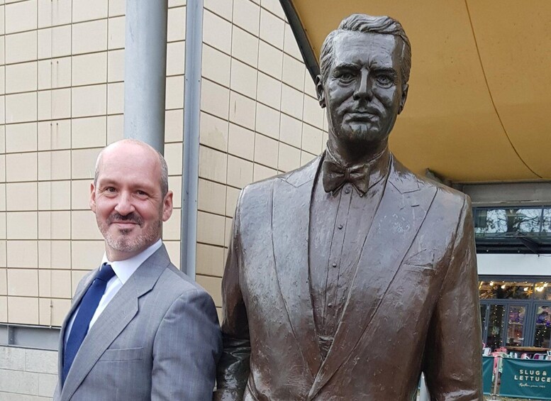 A man in a suit standing next to a bronze statue of a man in a suit. 2