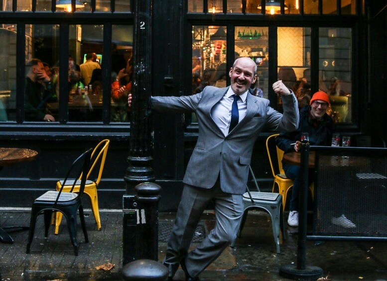 A man in a grey suit dancing on a city street. 1