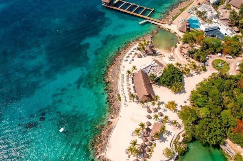 Un resort costero con playa, aguas turquesas cristalinas y un muelle. 5