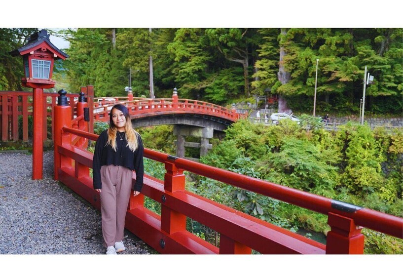 A person standing on a red bridge with a traditional Japanese lantern in the background. 4
