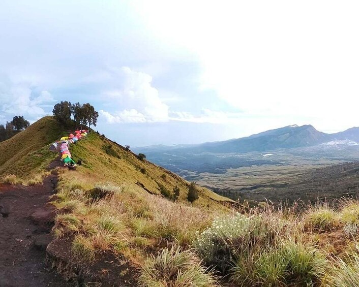 A hiking trail with colorful prayer flags on a grassy hill. 3