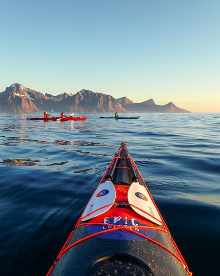 A kayak with 'EPIC' written on it, two other kayaks in the background, and a mountainous landscape. 3