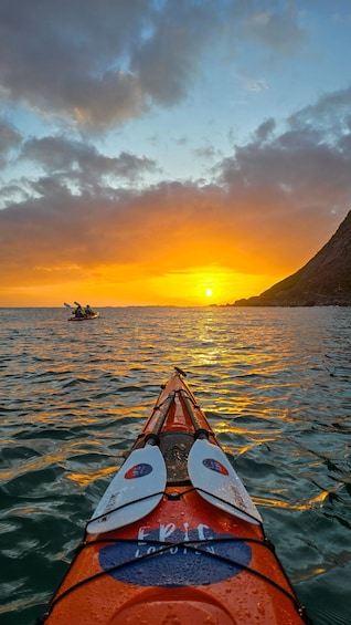 A kayak on calm water with a sunset in the background. 1