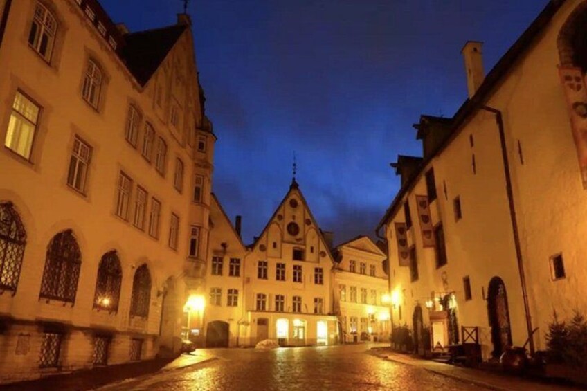 A historic European town square at dusk with illuminated buildings and cobblestone streets. 2