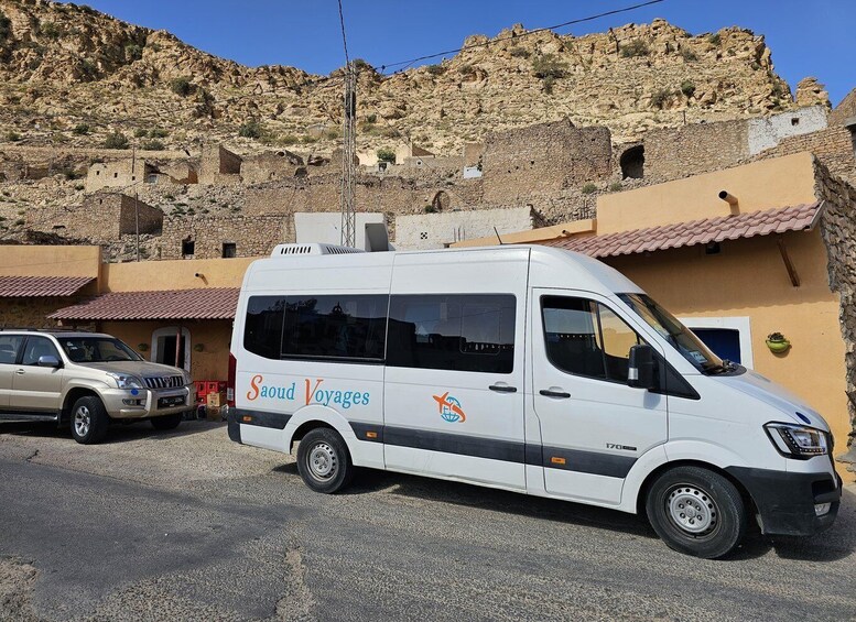 A white van with 'Saoud Voyages' branding parked in front of a building with a red-tiled roof. 4