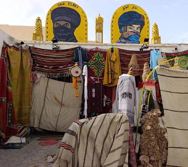 A tent with colorful fabrics and a mural of a masked figure. 3