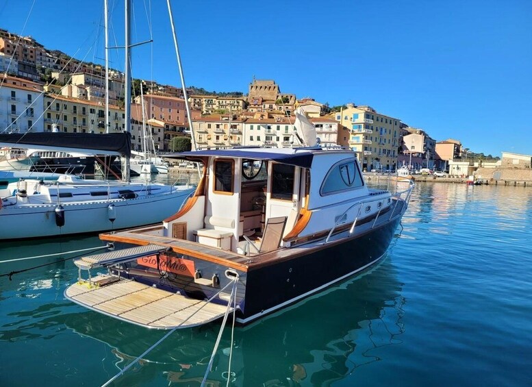 A yacht docked at a marina with buildings in the background. 2