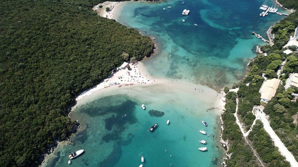 An aerial view of a coastal area with a beach, boats, and dense forest. 1