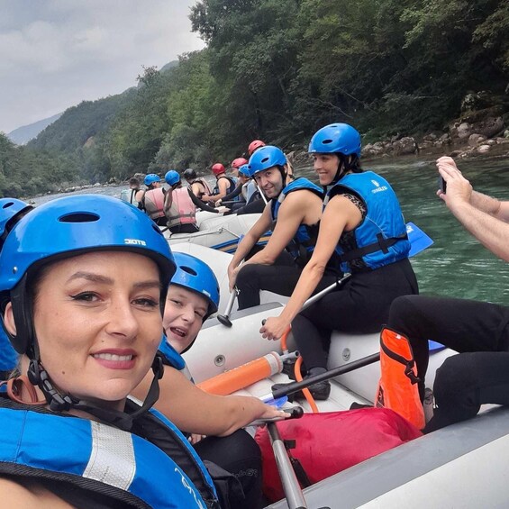 A group of people in a raft on a river surrounded by greenery. 4