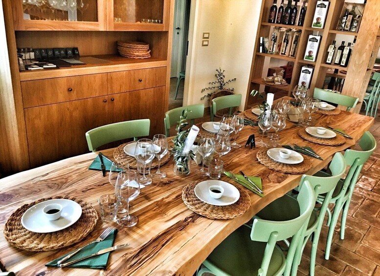 A wooden dining table set with plates, glasses, and cutlery, surrounded by green chairs. 3
