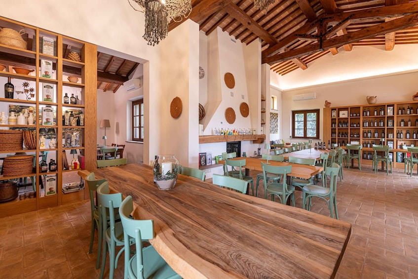A rustic interior with wooden tables, green chairs, and shelves of bottles. 2