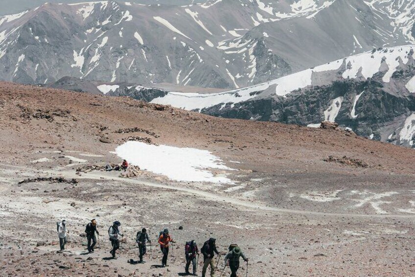 En grupp vandrare på en bergstig med snöfält och stenigt underlag. 5