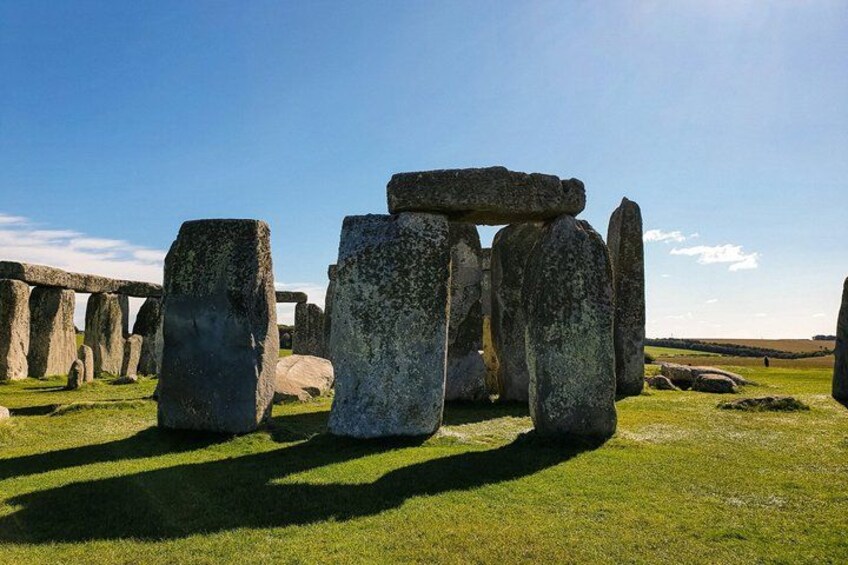 Stonehenge standing in a grassy field with clear blue sky. 1