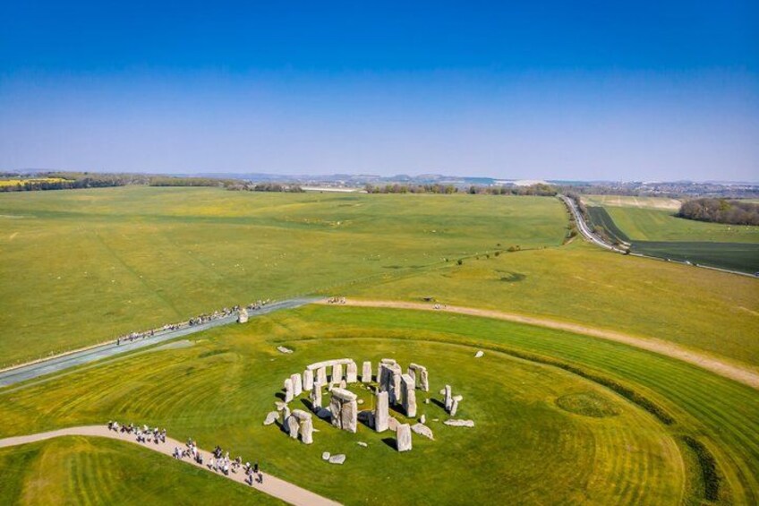 Stonehenge, a prehistoric monument, surrounded by green fields and a clear sky. 2