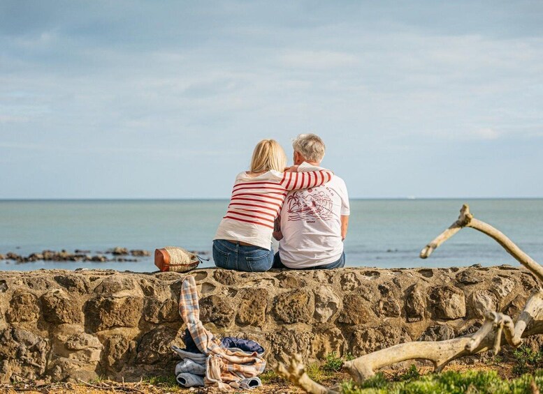 A couple sitting on a stone wall by the sea, overlooking the water. 4