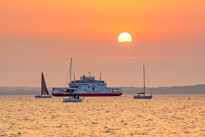 A sunset over a calm sea with a ferry named 'Red Funnel' and sailboats. 1