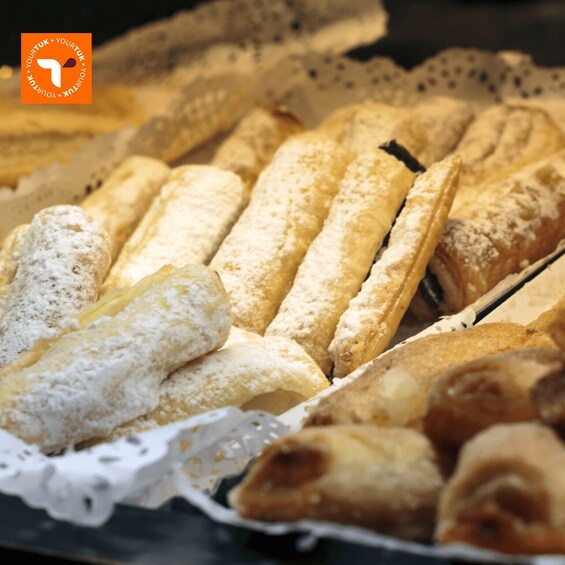 A variety of pastries, including éclairs and croissants, arranged on a tray. 5