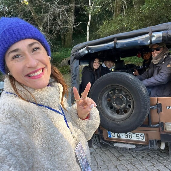 A person in a fluffy white jacket and blue beanie making a peace sign. 3