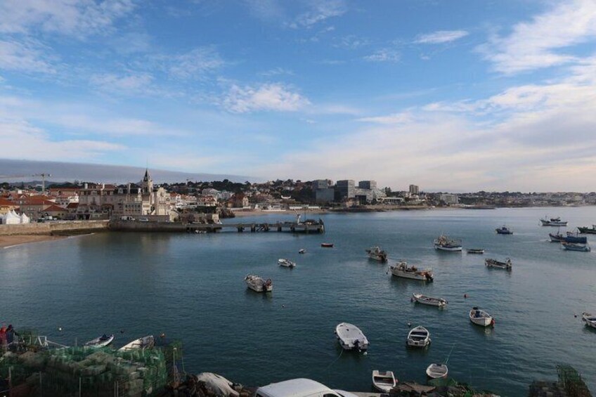 Un puerto con varios barcos, un edificio destacado con torre y un paisaje urbano distante. 2
