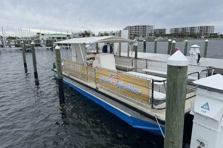 A boat docked at a marina with a wooden deck and a blue hull. 1