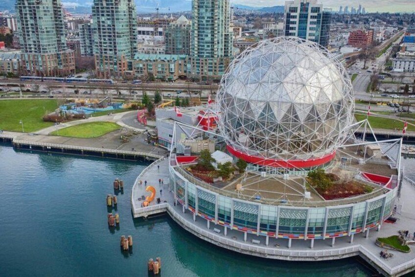 A large geodesic dome structure with a circular base, surrounded by water and urban buildings. 2