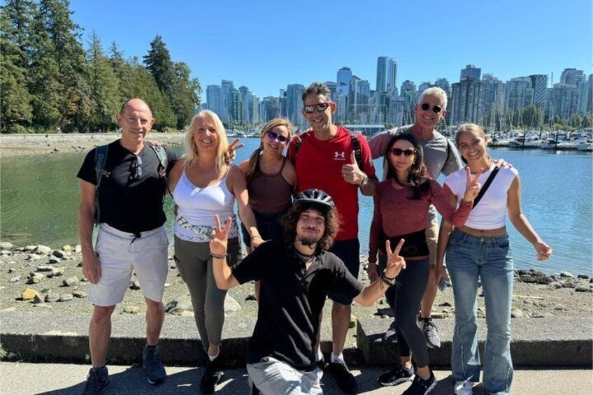 A group of people posing by a waterfront with a city skyline in the background. 1