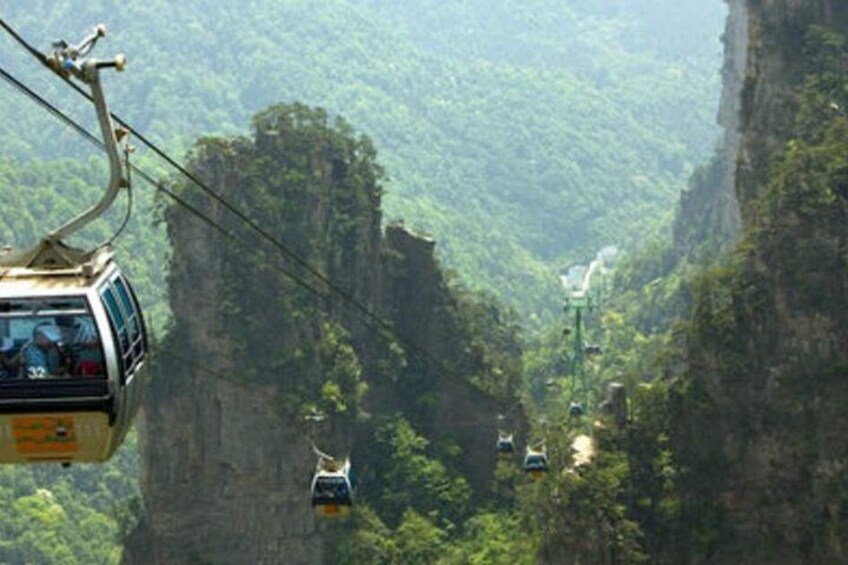 A cable car system in a mountainous area with steep cliffs and dense greenery. 3