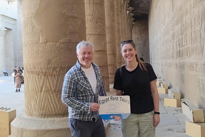 Två personer står framför antika egyptiska kolonner, och en skylt visar texten ”Egypt Rest Tours”. 1