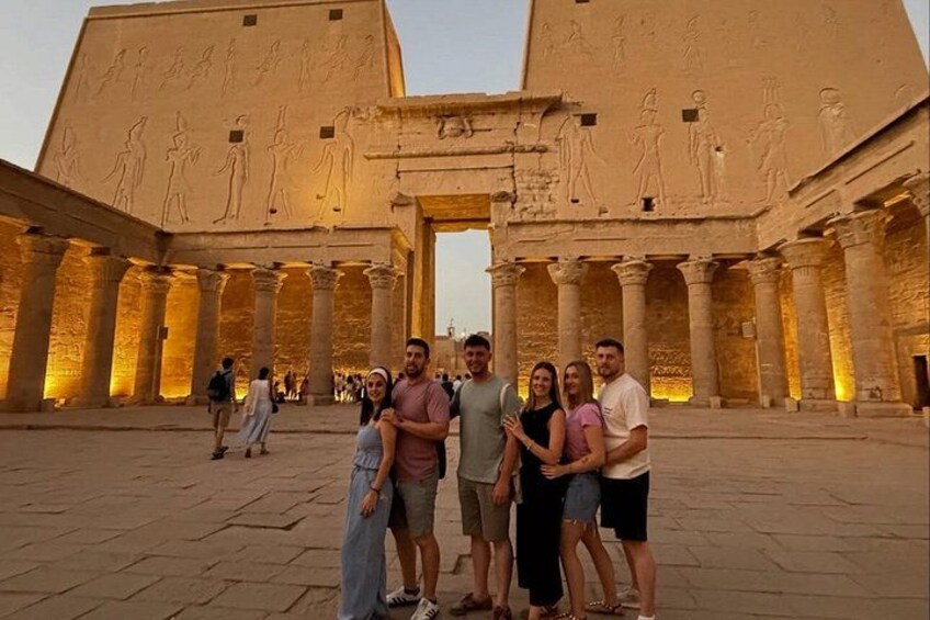 En grupp människor som står framför ett forntida egyptiskt tempel med hieroglyfer och pelare. 2