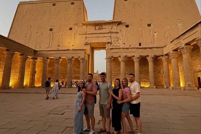 En grupp människor som står framför ett uråldrigt egyptiskt tempel med hieroglyfer och pelare. 5