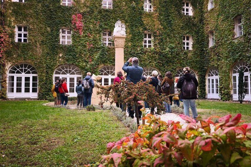 A courtyard with people, a statue, and ivy-covered walls. 2