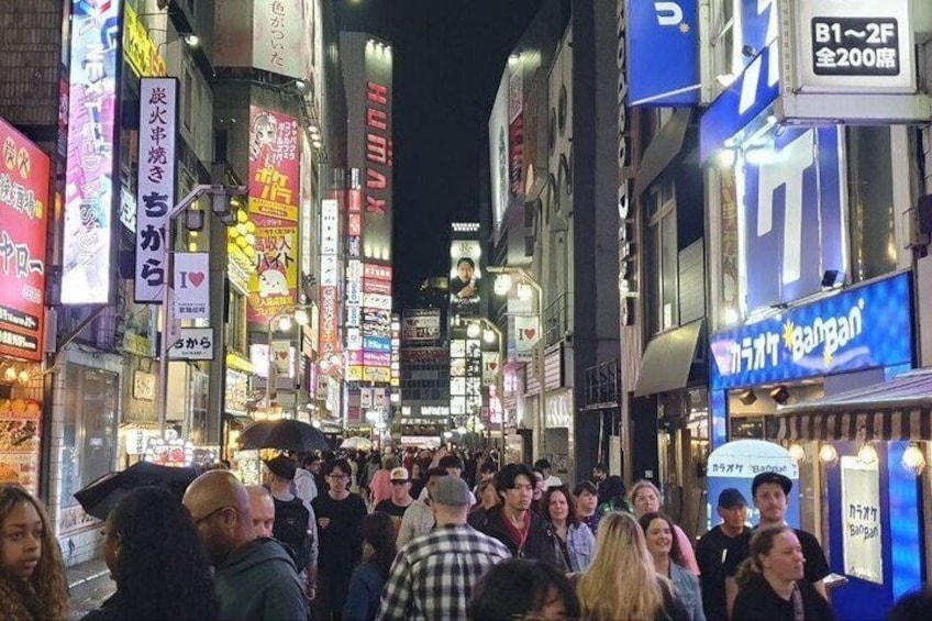 A busy urban street at night with illuminated signs and storefronts. 2