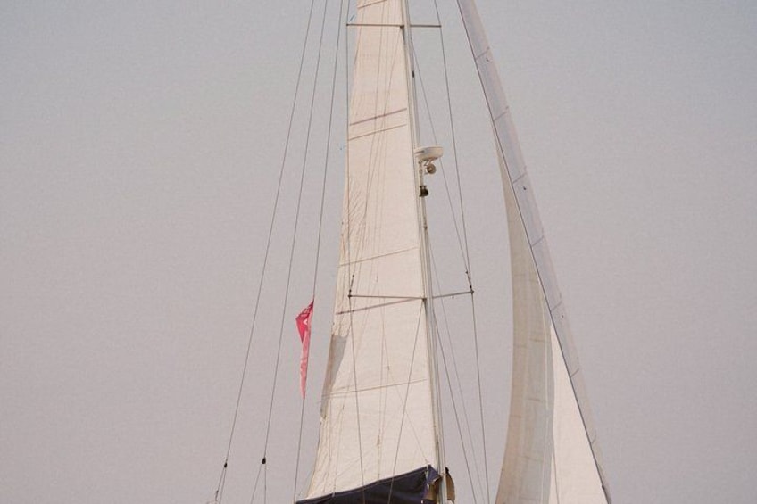 Een zeilboot met een witte zeil en een rode vlag. 4