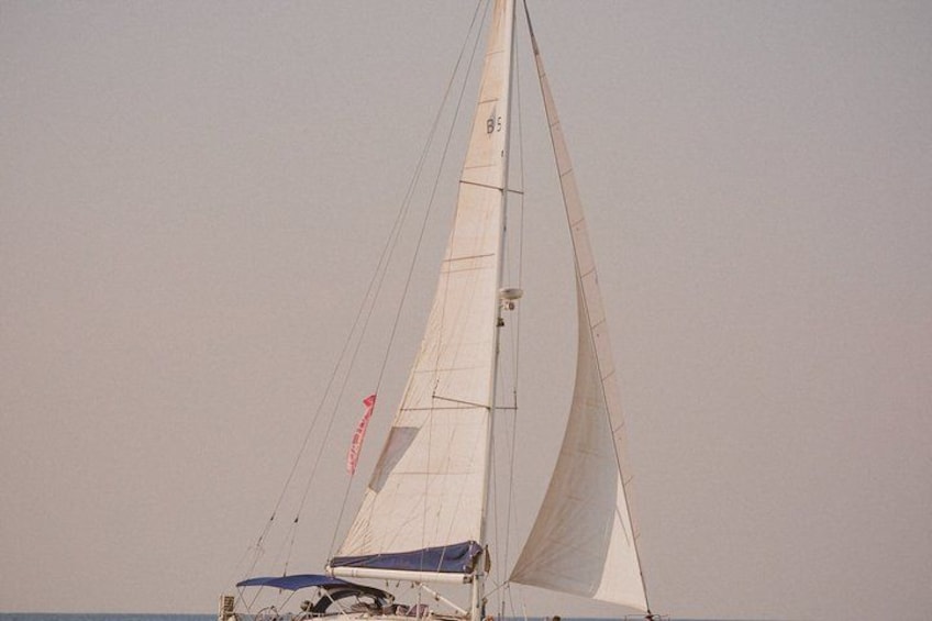 Een zeilboot met een witte zeil en een blauwe kajuit. 3
