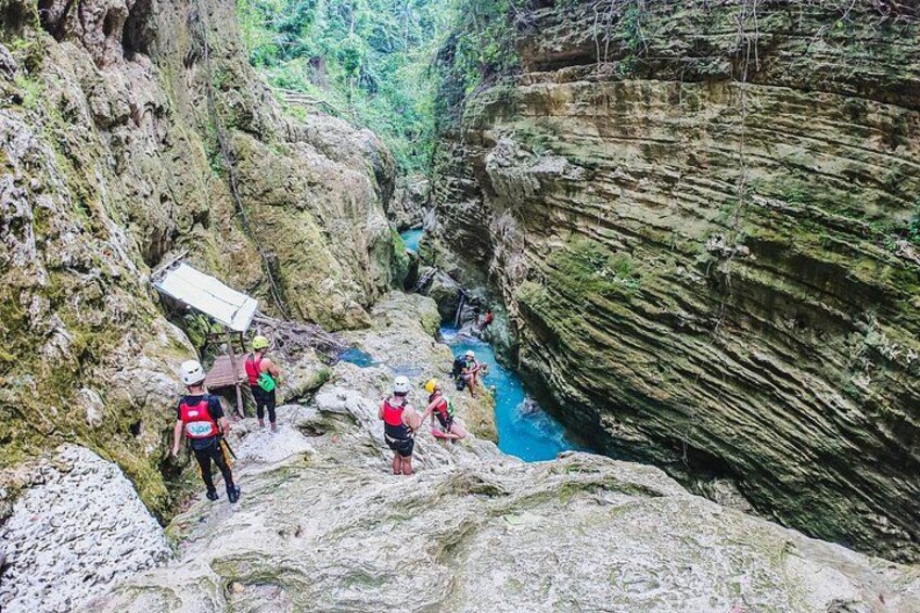 A group of people hiking in a rocky canyon with a river. 2
